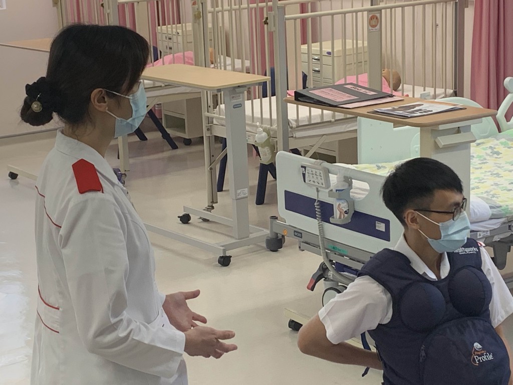袁海鑌（右）模擬孕婦，朱慧玲（左）從旁介紹護士該如何照顧孕婦。