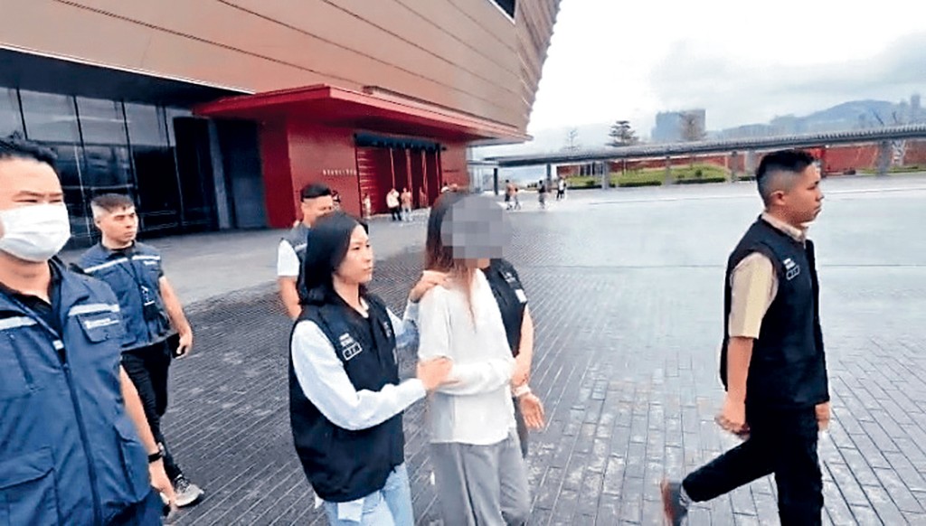 涉嫌未經批准在港從事導遊工作被捕的一名內地女子由入境處人員押走。