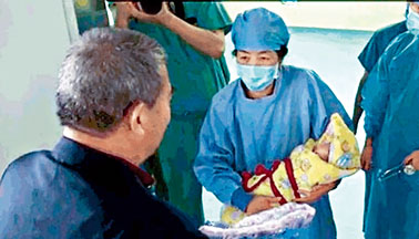 ■医生抱出据称是六十七岁女子产下的女婴给其六十八岁的父亲。