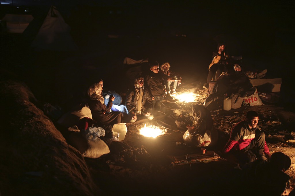 流離失所的巴人在夜間點火取暖，正等候返回加沙北部家園。美聯社