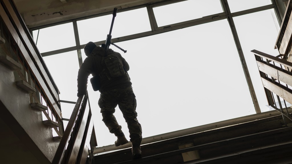 在赫尔松地区的战争中，一名乌克兰狙击手兼指挥官走进一栋建筑。 美联社