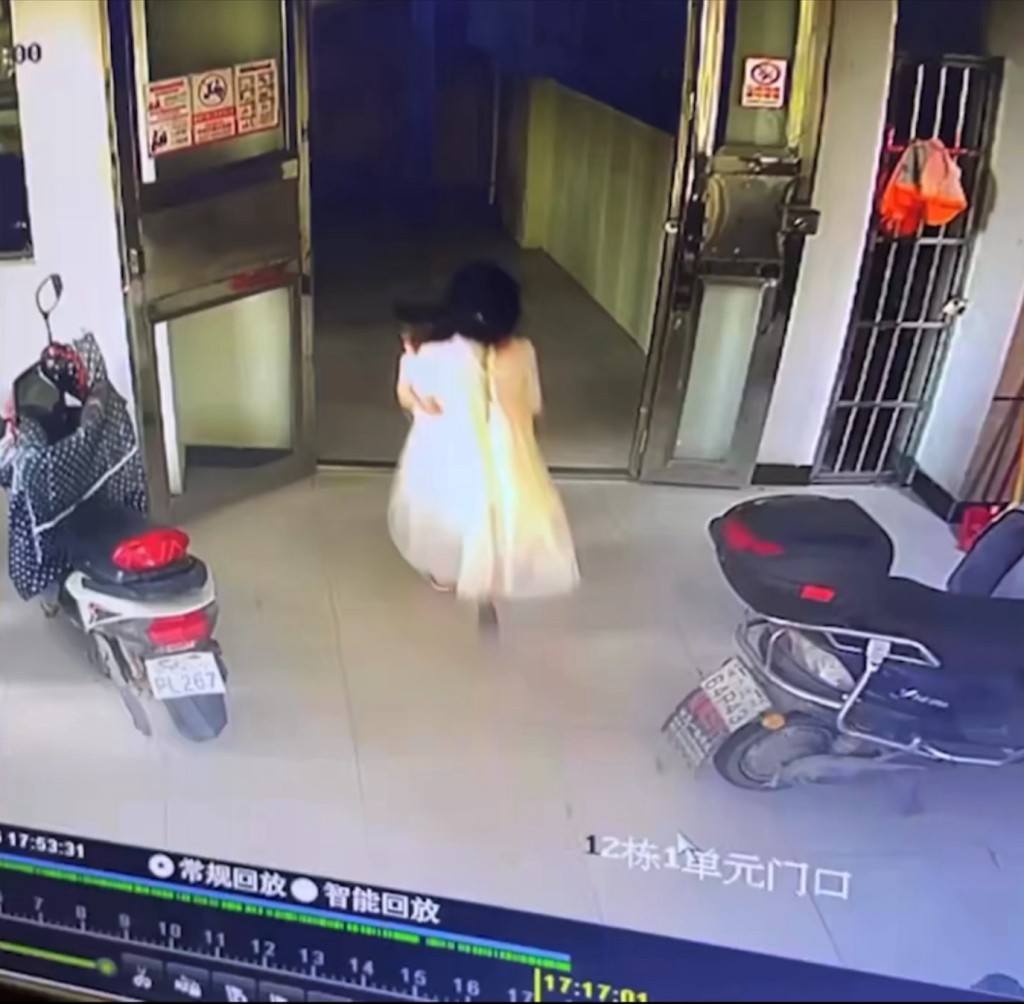監控錄像拍下身穿白裙的女孩抱着秦秦走進大廈。