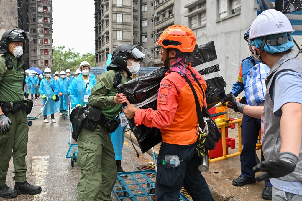 警務人員和民眾安全服務隊隊員，聯同地區服務及關愛隊伍義工，同心合力，協助上樓居民搬走物品。