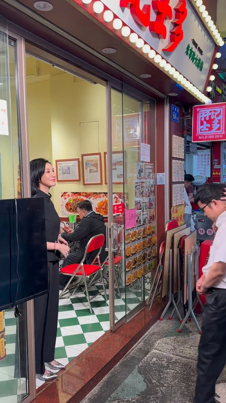 關秀媚在廣州街頭的店鋪門外準備拍攝，身形纖瘦。