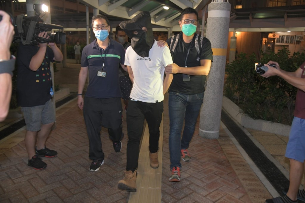 疑犯(白衣)被警方帶回寓所調查。