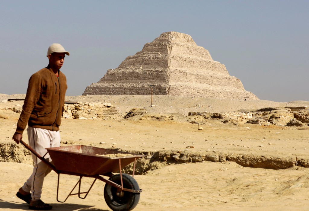 一名工人走在金字塔前。路透資料圖