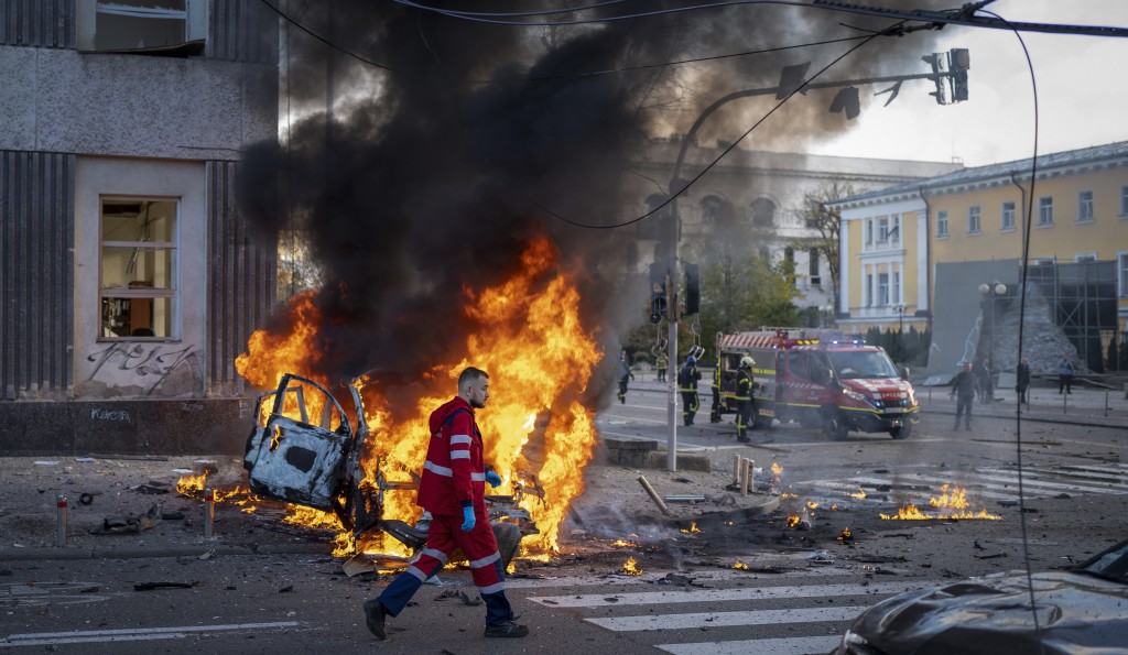 俄羅斯在烏克蘭基輔發動襲擊後，一名醫務人員跑過一輛燃燒的汽車。AP