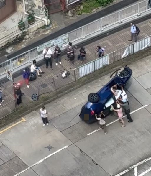 Tesla翻側司機被困，現場多名熱心途人協助救人。fb「全港交通關注組🇭🇰」影片截圖