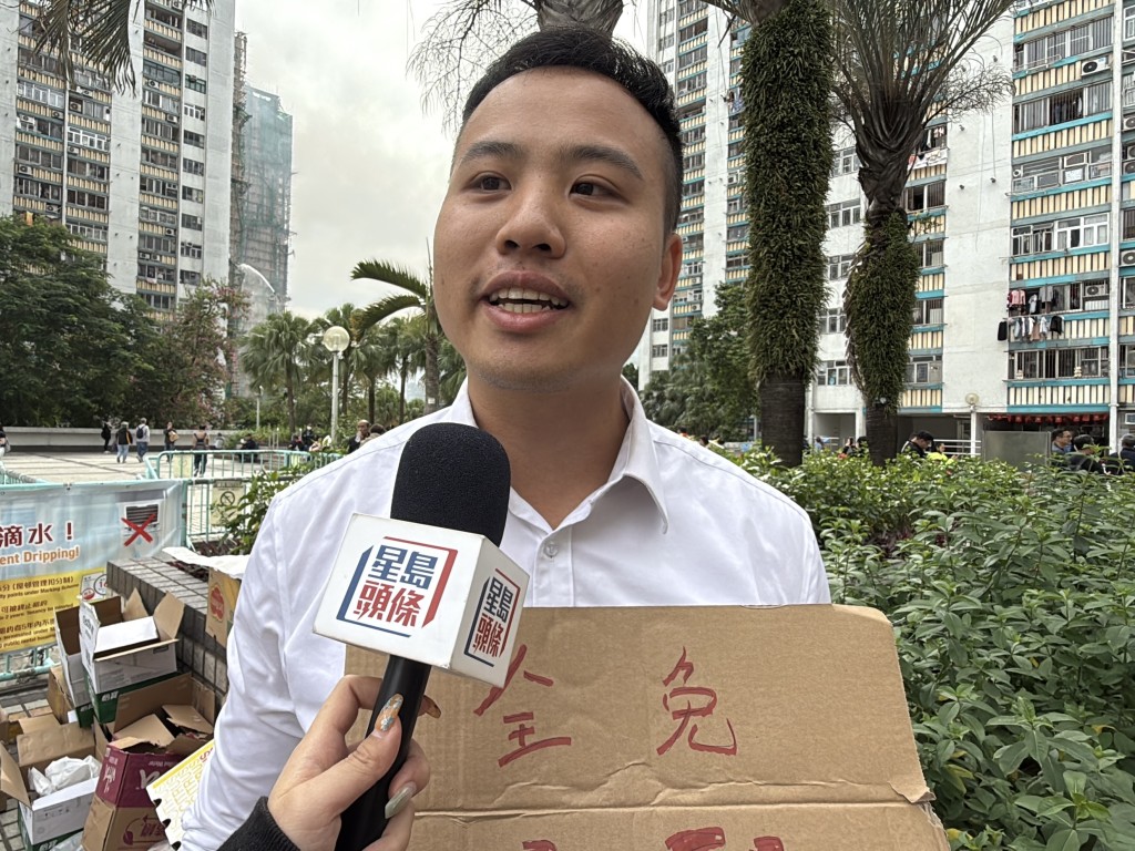 中醫師趙先生手持「全免中醫針灸鐵打」的紙牌，為災民提供免費診治服務。