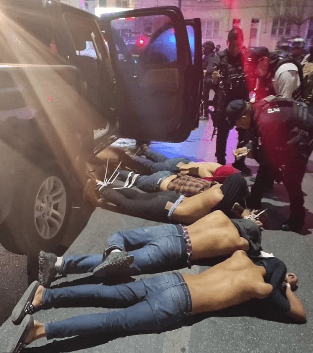 网传照片可见，5名男子脸朝下趴在行人道，上衣被拉到脸部，身穿制服的执法人员站在一旁。