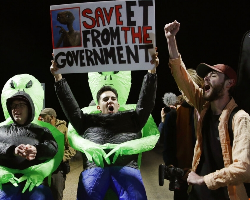 部分民众戴著锡纸帽及外星人面具，其他人士手持标语，上面写著「把外星人从政府释放出来吧！」　AP
