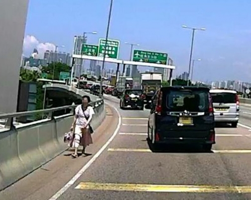 妇人在路肩逆向行走。