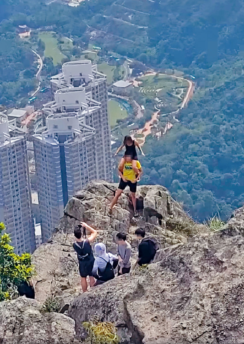 兩男女在自殺崖附近峭壁上玩騎膊馬，由同行者拍攝。