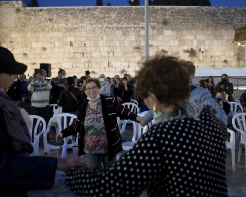 以色列昨日（11月30日）起慶祝光明節，部分人除口罩牽手跳舞。（美聯社）