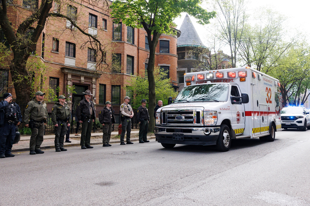 一輛載著殉職警員遺體的救護車駛過，送葬隊伍緩緩行進。 美聯社