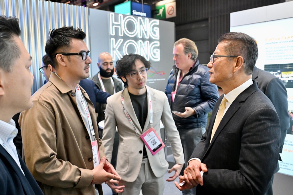 陳茂波（右一）到訪展覽會的香港館，與參展的香港企業代表交談。政府新聞處