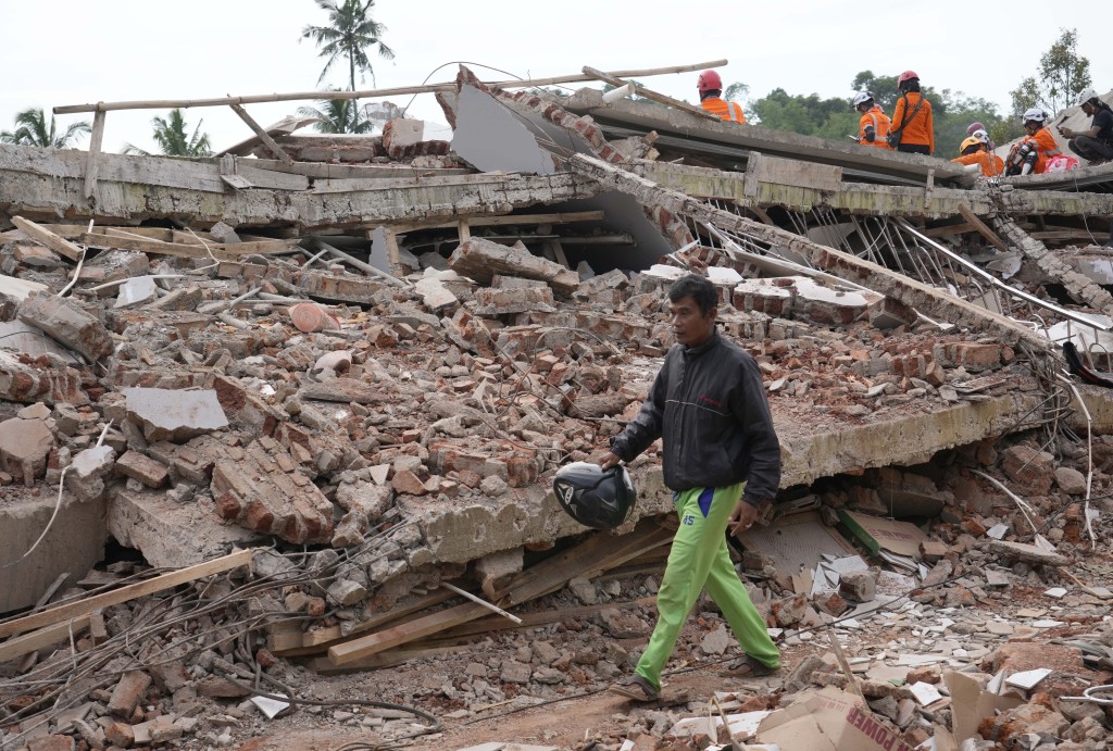 印尼西爪哇一名男子走过地震中倒塌的建筑物废墟。AP
