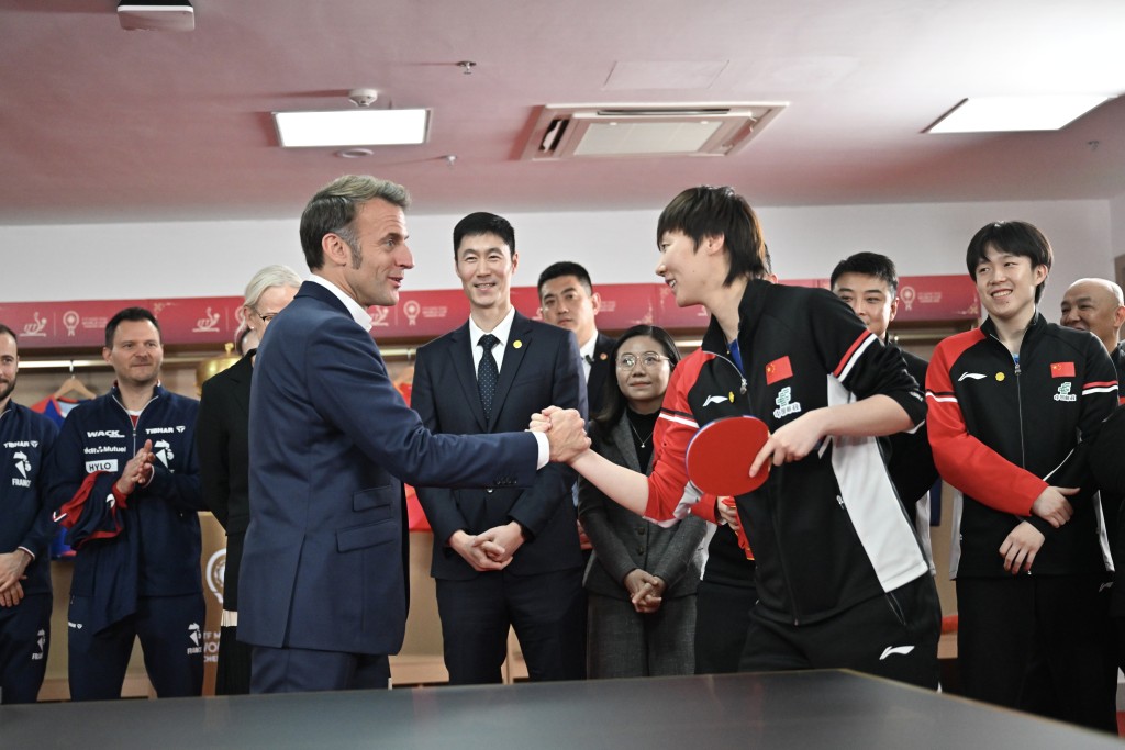 馬克龍與中國隊球員王曼昱握手。中新社