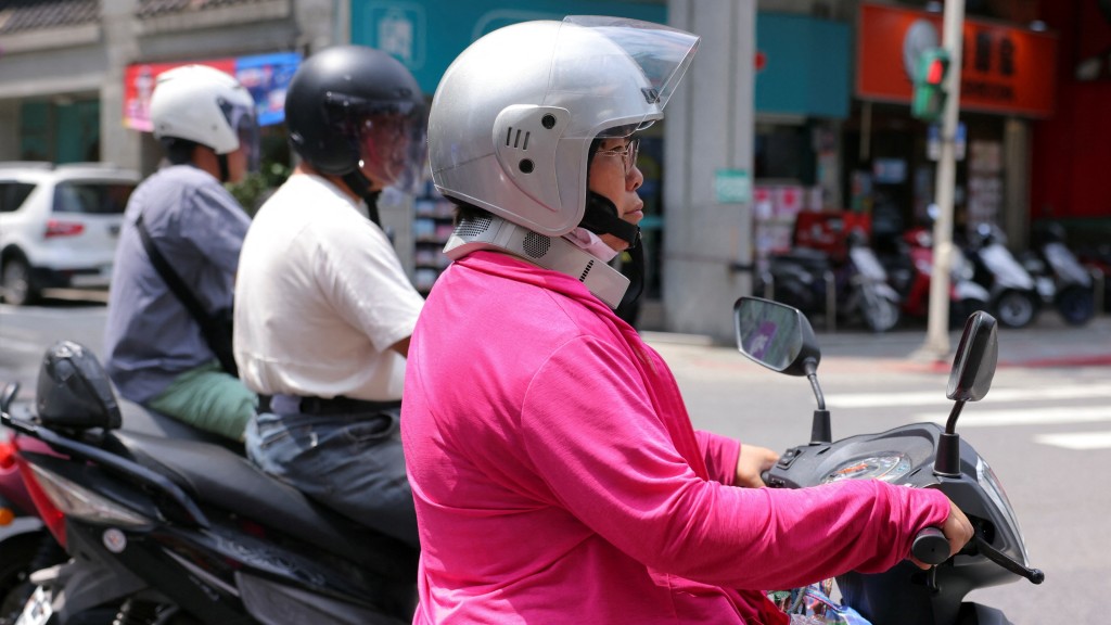 近年推出掛頸式風扇，台北女子邊吹邊開電單車。 路透社