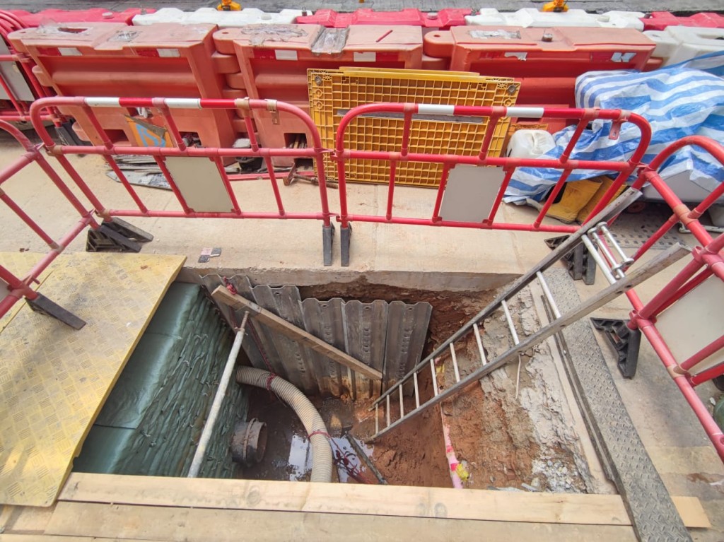 工人爬铝梯回路面之际，跣脚跌回地底。 梁国峰摄