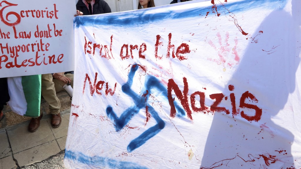 國際法院 （ICJ）外的示威者手寫橫額，諷刺「以色列是新納粹」。 路透社