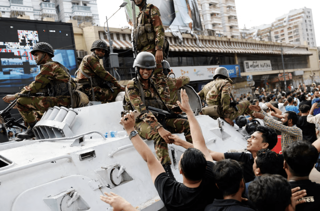 2024 年 8 月 5 日，孟加拉国达卡，人们在庆祝孟加拉国总理哈西娜辞职，并与军队人员握手。路透社