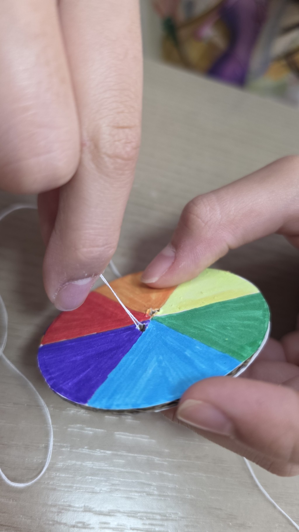 步驟2:在靠近圓心兩旁位置各開一個小孔,將繩穿過兩個小孔,再打結成一個圈,「手拉飛輪」就完成了。(圖片來源:工程師媽媽Yanny) 步驟2:在靠近圓心兩旁位置各開一個小孔,將繩穿過兩個小孔,再打結成一個圈,「手拉飛輪」就完成了。(圖片來源:工程師媽媽Yanny)