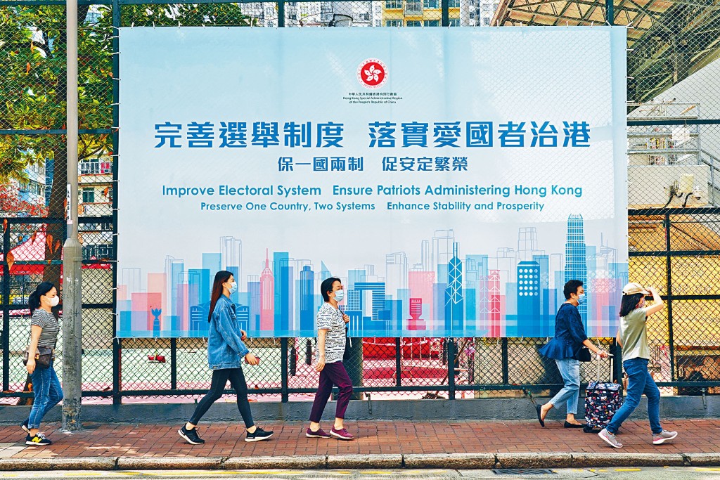 ■市民在旺角街頭步過完善選舉制度,落實愛國者治港廣告牌。