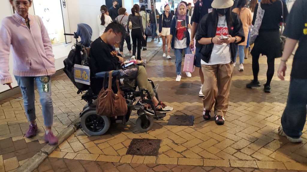 銅鑼灣渣甸坊有殘障人士坐在輪椅上乞討，並贈送糖果予施捨者。 尹敬堂攝