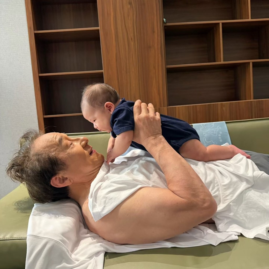 72歲的成龍大晒驚人結實的「麒麟臂」，半躺梳化上將BB平托在胸前。