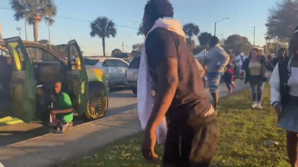 在佛羅里達州皮爾斯堡市，槍擊案發生後，有人繼續跑、有人躲在車後。網片截圖