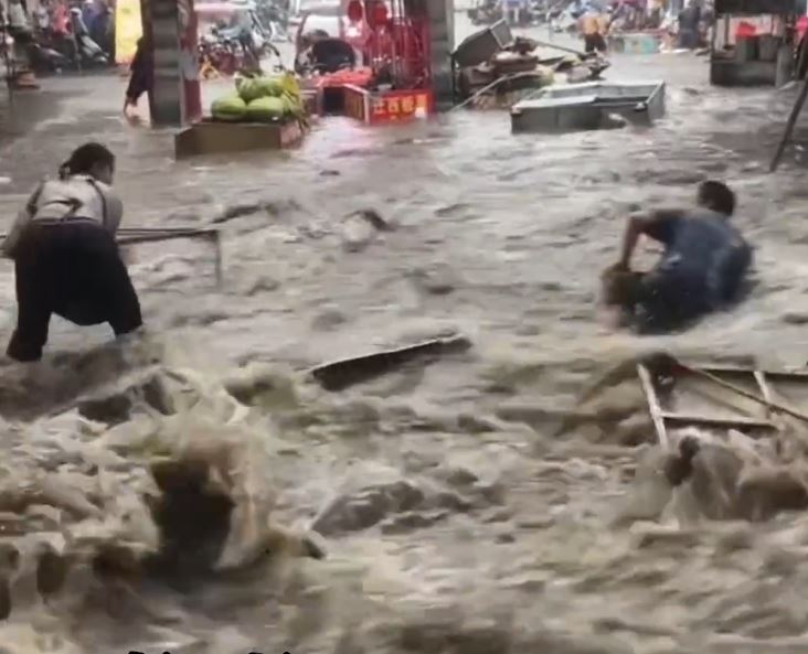 陕西长安区韦曲老街积水严重，有人拼命浸在积水中，企图保住被冲走的财物。