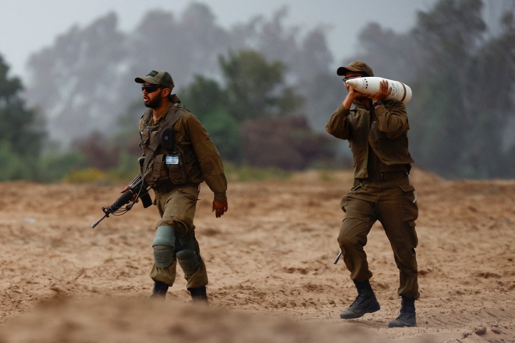 以軍在加沙的軍事行動持續，一名士兵抬著一枚炮彈。路透社