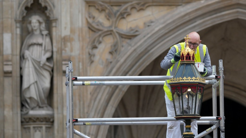 英王查理斯三世的加冕典禮在即，工人補油粉飾白金漢宮外的街燈。 美聯社