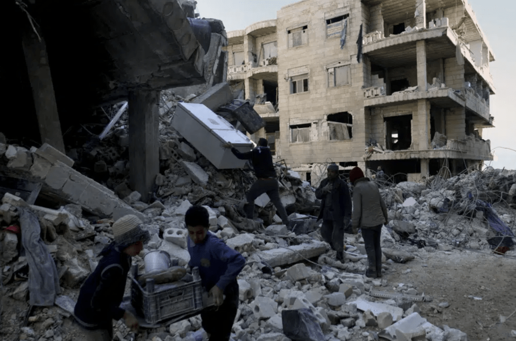 在敘利亞阿勒頗省金德里斯鎮，人們從倒塌的建築物中取出家具和家用電器。AP