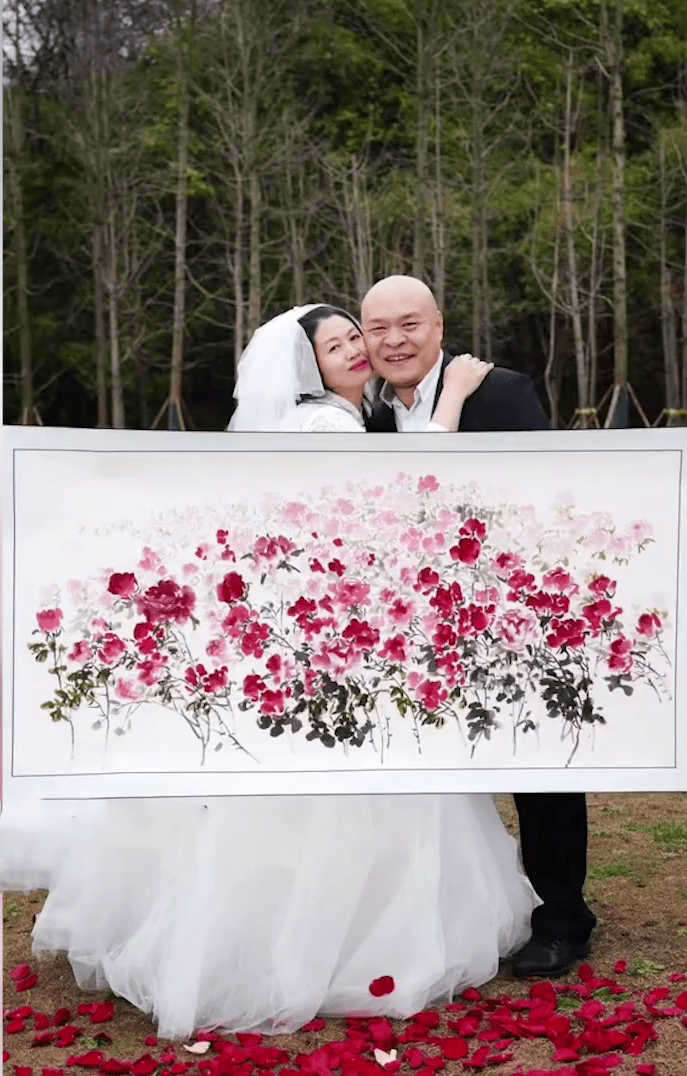 夫妻倆同框拍照，並將所畫的玫瑰花畫作放在正中間。