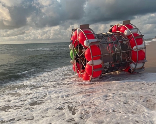 探險家巴盧奇圖以浮桶裝置海上步行到紐約，但設備故障被沖上海灘擱淺。網圖