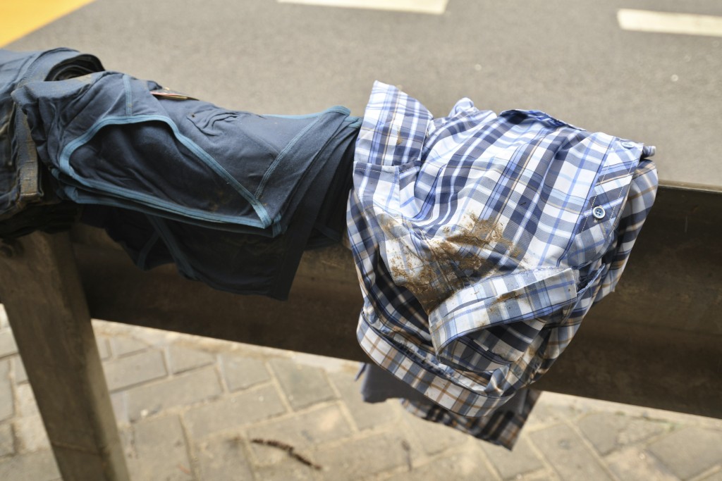 有街檔的衣物被黃泥水污染，置於路邊防撞欄上曬乾。(陳浩元攝)