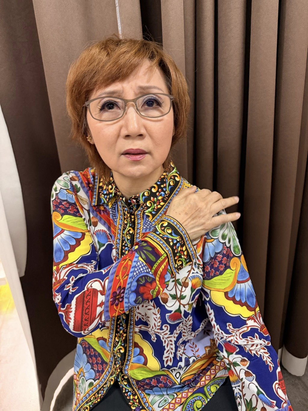 4月15日，張德蘭右手撳着左手的肩膊，神情略見痛楚。