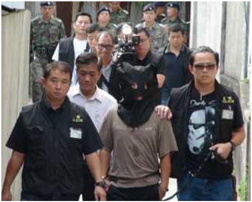 被告阮文強以黑布蒙頭由警方帶回現場重組案情。資料圖片