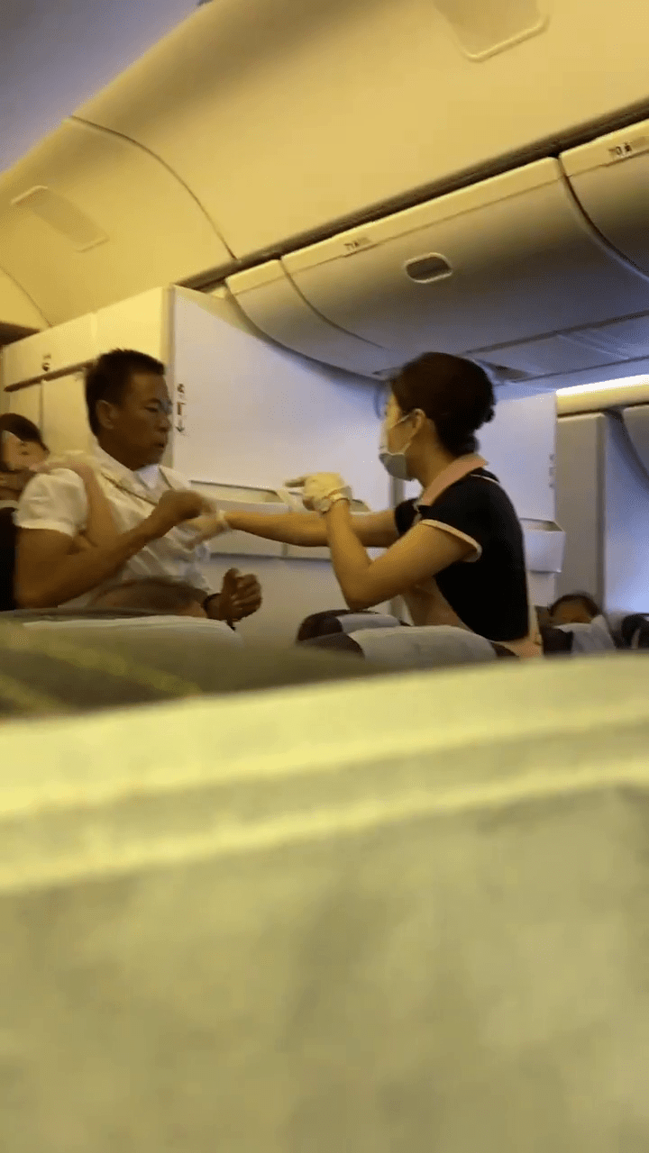 被肘击的空姐仍紧紧抱著白衫男阻止他打人。