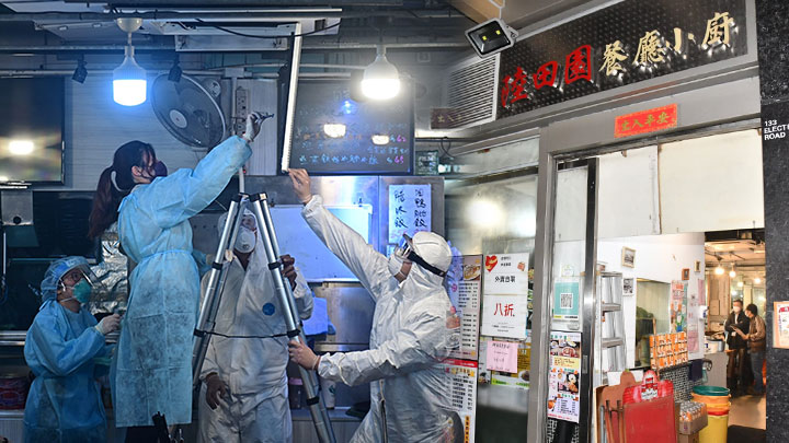 有人爬上長梯並以電筒檢查設於餐廳天花板的通風口。