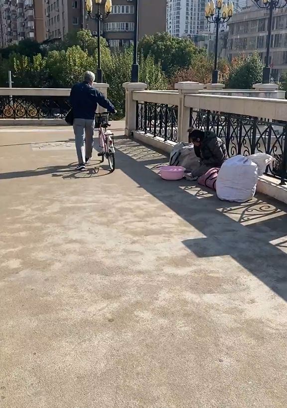 男乞丐跪在天橋上行乞。影片截圖