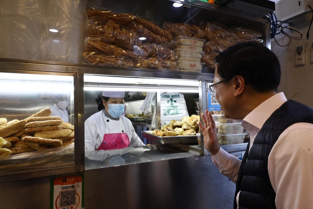李家超到访外交部前，与驻京办员工共晋早餐，与食店员工打招呼。（李家超fb图片）