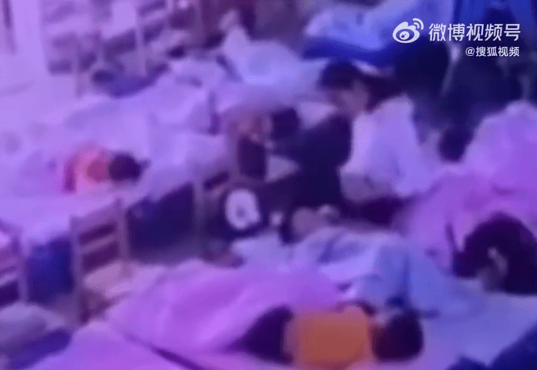 保育員在一名睡在床上的幼兒拿出膠紙。