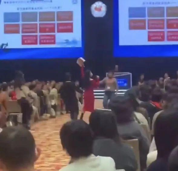 紅衫女手持咪高峰，手裡拿著一疊紙，大聲喊道：「華南區銷售總監程某某，白嫖我14年！」