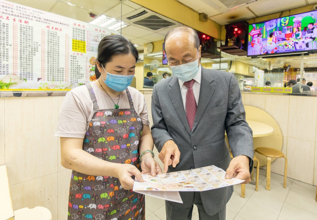 尹志田(右)向參與食肆的負責人介紹「關懷有饍」計劃。