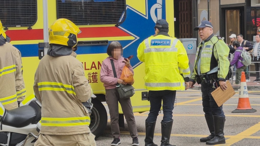 警員向女傷者的同行親屬了解事發情況。