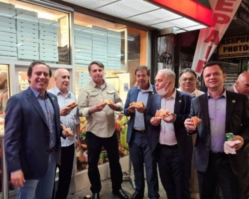 巴西總統博索納羅（左起第三）與其他訪團官員一起在路邊吃披薩、喝可樂。網圖