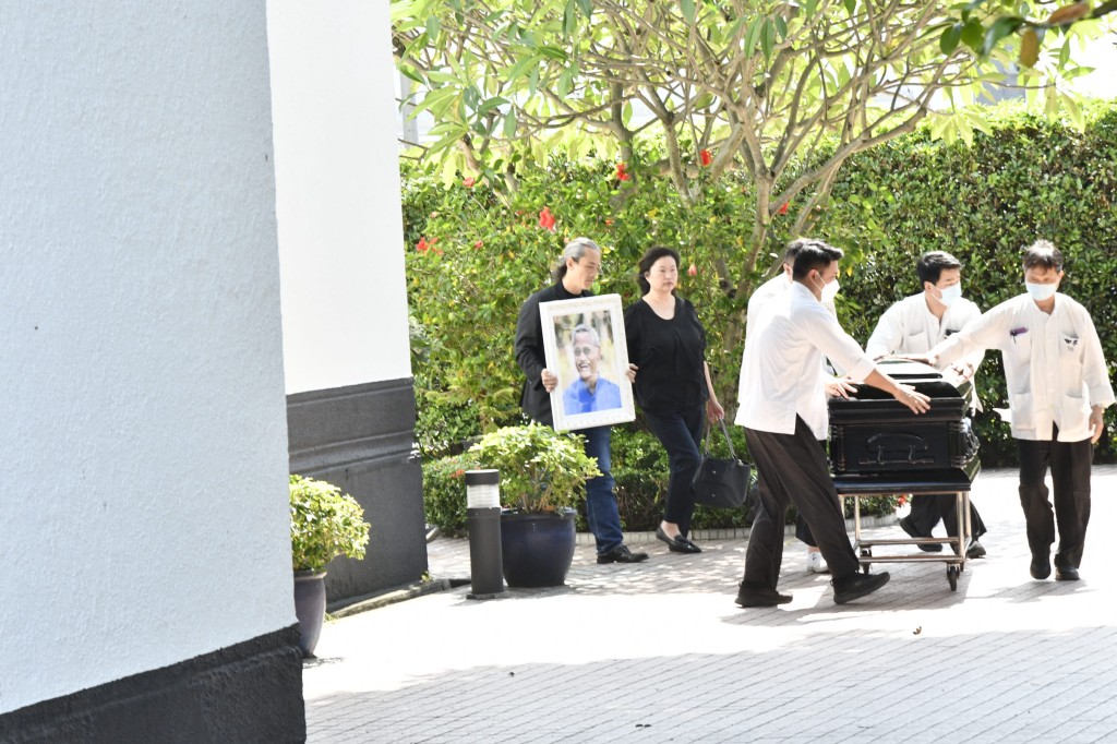 吳嘉龍捧着亡父吳耀漢的遺照,隨靈柩步出教堂。 吳嘉龍捧着亡父吳耀漢的遺照,隨靈柩步出教堂。